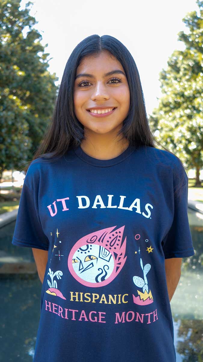 Marily Mata stands in front of one of the reflecting pools on the UTD campus, wearing her Hispanic Heritage Month t-shirt design.